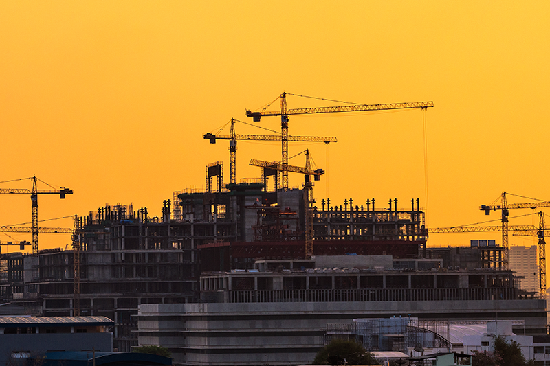 Construction cranes and building framework at sunset