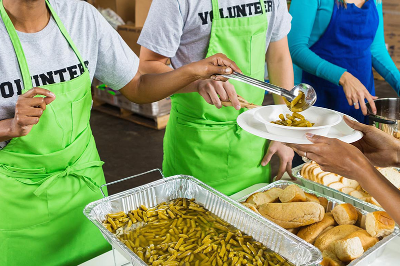 Volunteers serving food at a community meal station